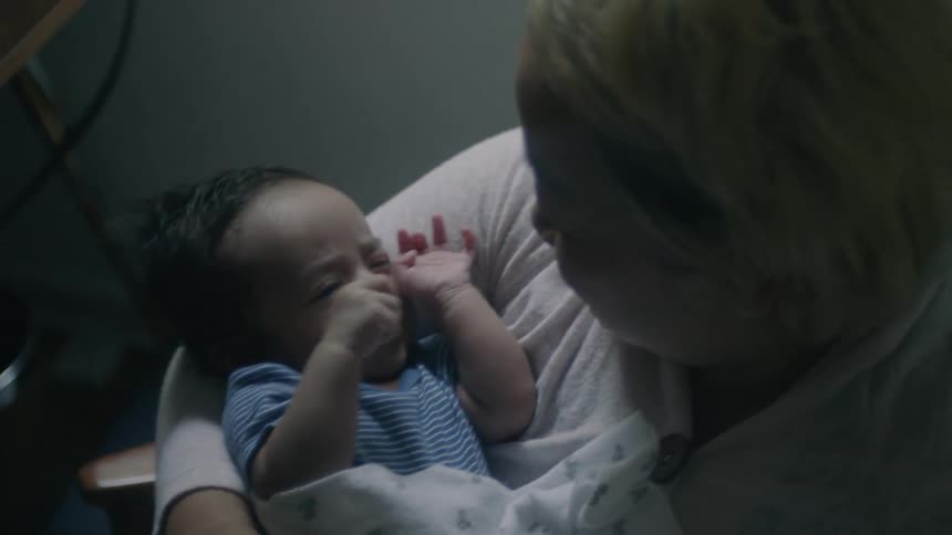 A woman cradles a baby who is waving his hands