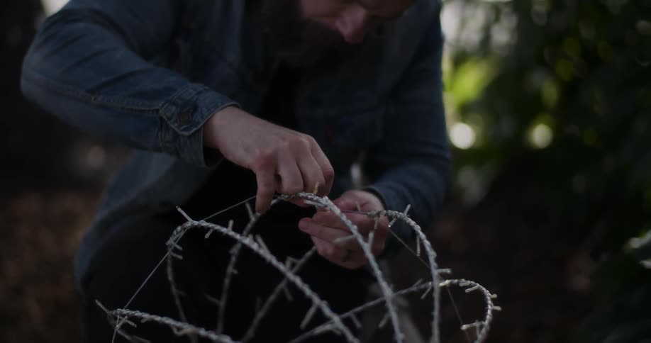 A man puts up christmas lights in the front yard