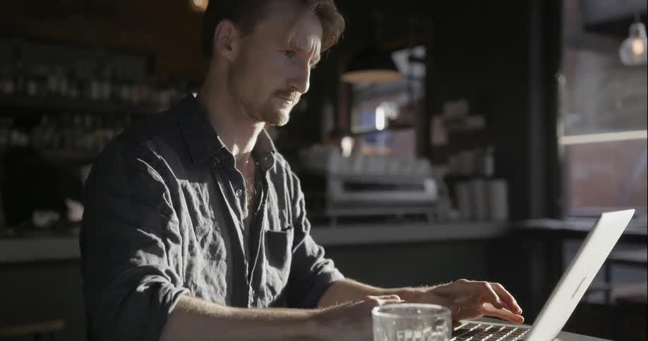 A man in a cafe works on his laptop