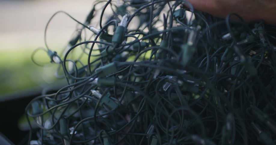 A man removes christmas lights from a crate on the front lawn