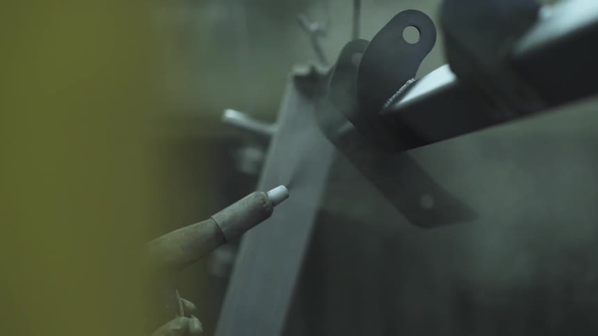 A man is spraying paint on some metal