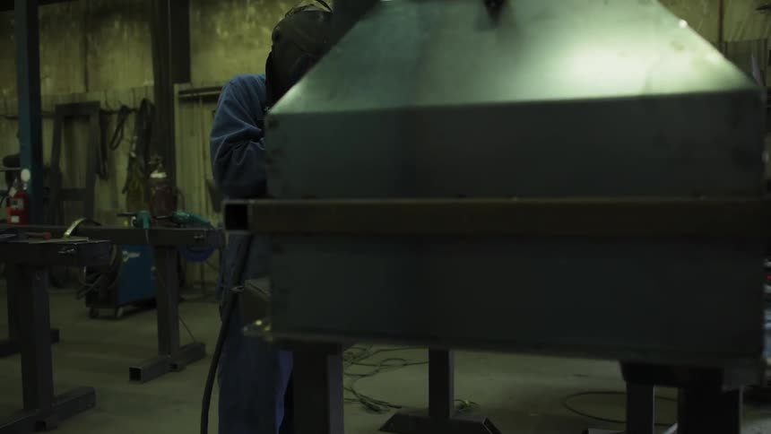 A shop has many machines and a man working with a torch