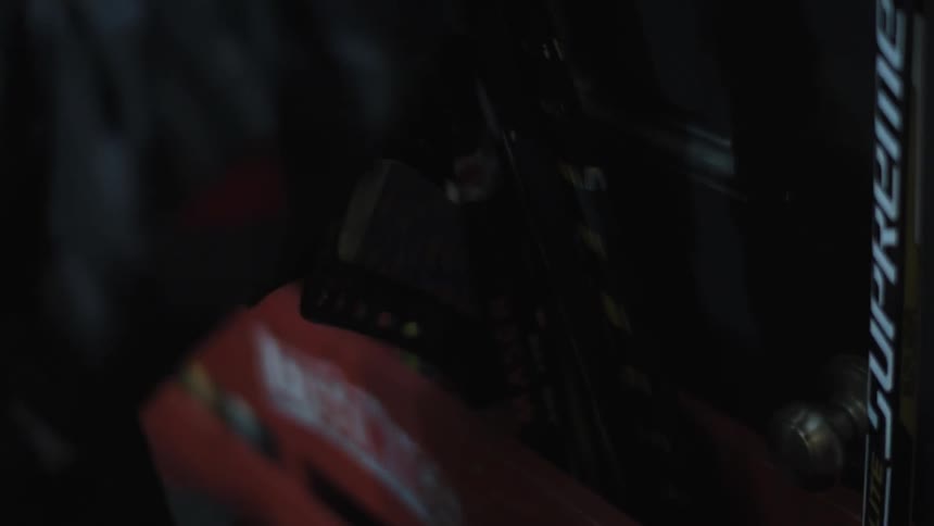 A person takes hockey sticks from a pouch on the wall