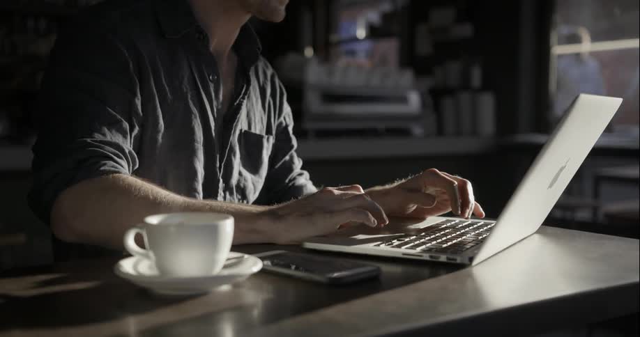 A man works on his laptop in a coffee shop