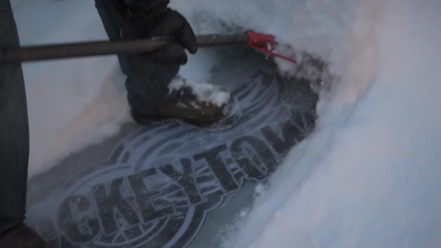 A man shovels snow from an ice rink