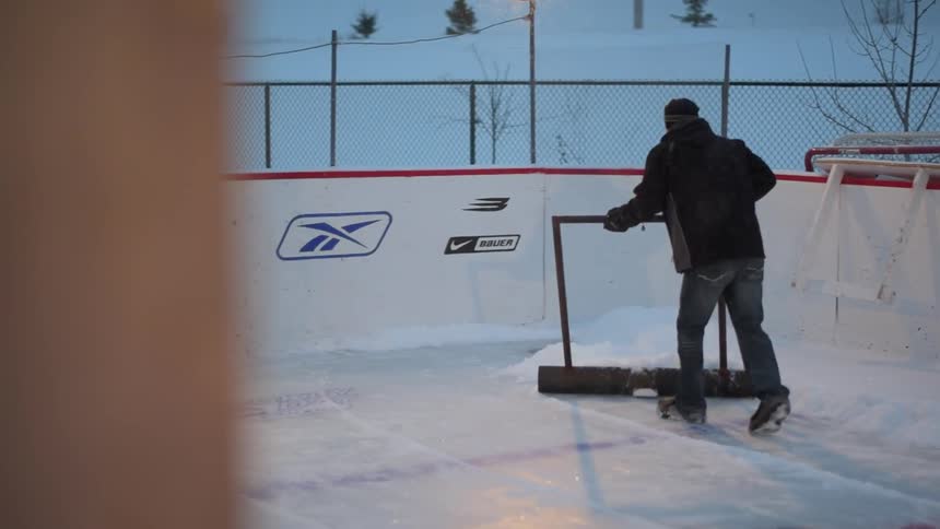 A man is shaving the ice in the ice rink