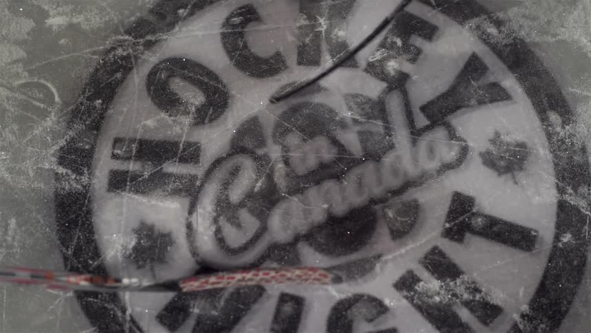 Hockey sticks hit at a puck on the ice