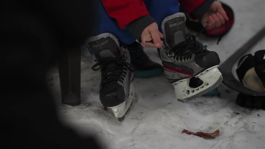 A man laces up his ice skates
