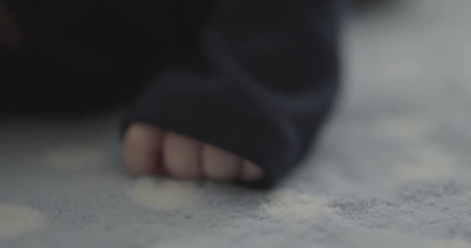 A baby is moving his hand around on the blanket