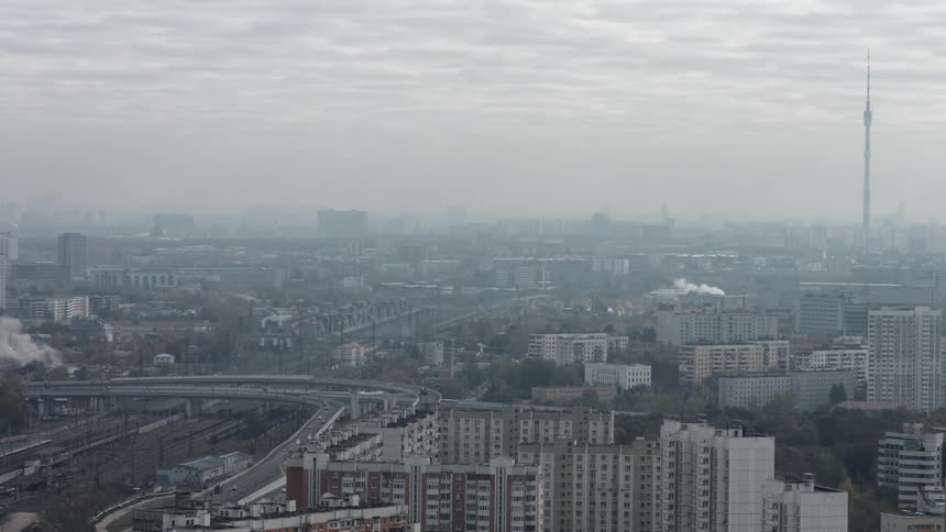Cars drive on a city highway as clouds pass overhead