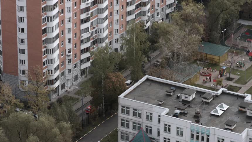 People are playing in the park near the apartment buildings