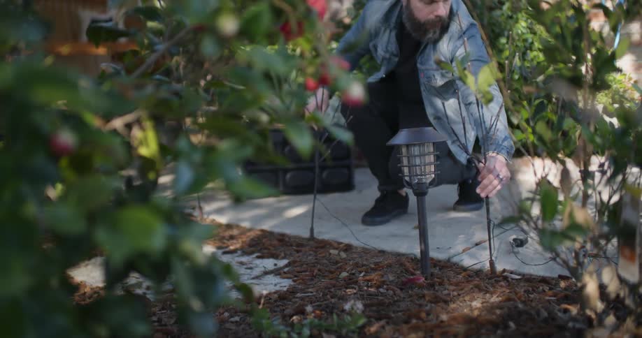 A man puts up christmas lights in the yard
