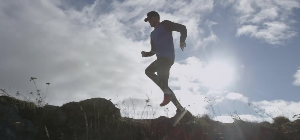 A jogger runs across rocky and uneven ground