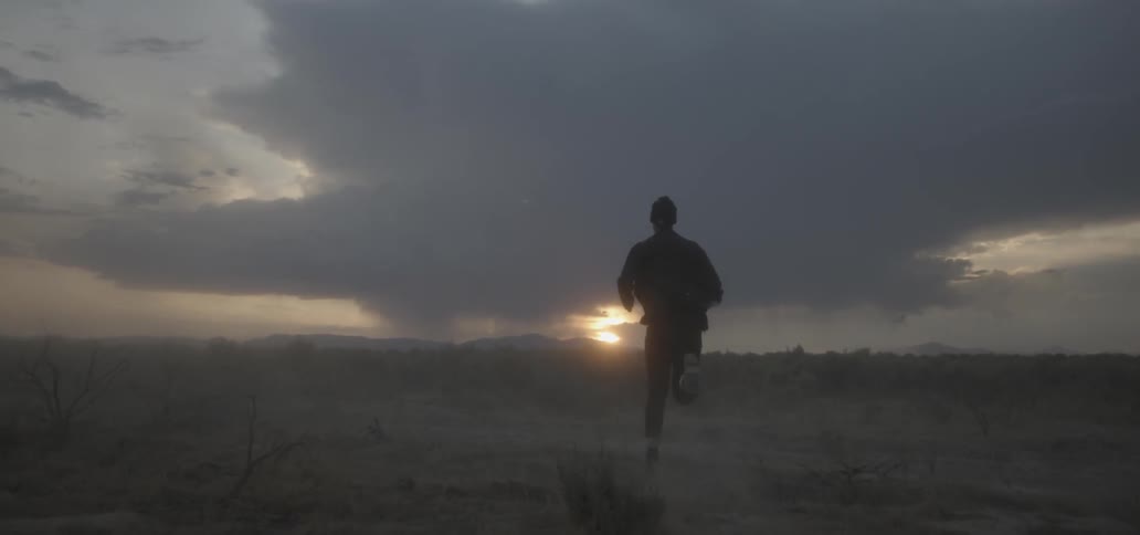 A man is jogging on a long trail at dawn