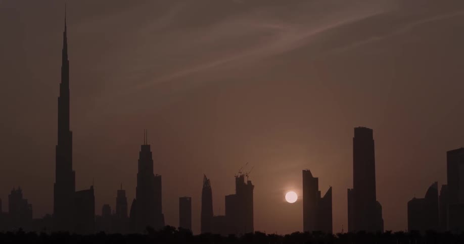The sun is setting in the cloudy sky of this city