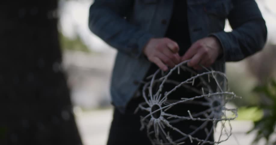 A man playing with a decoration that looks like a wire ball