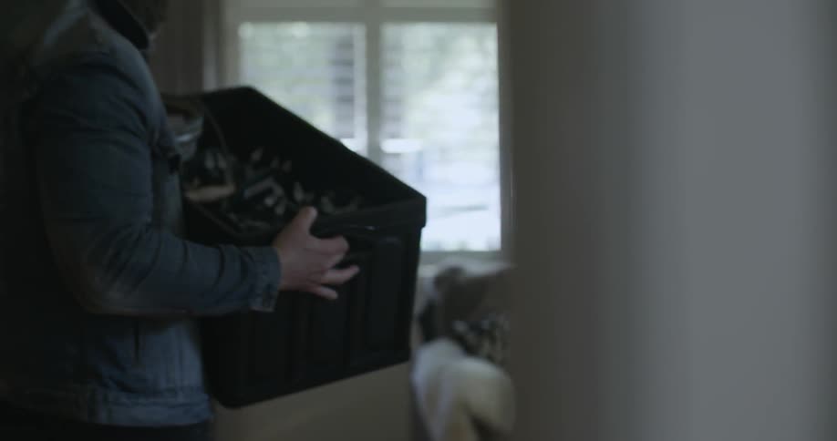 A man carries and sets down a box of decoration in his home during the day