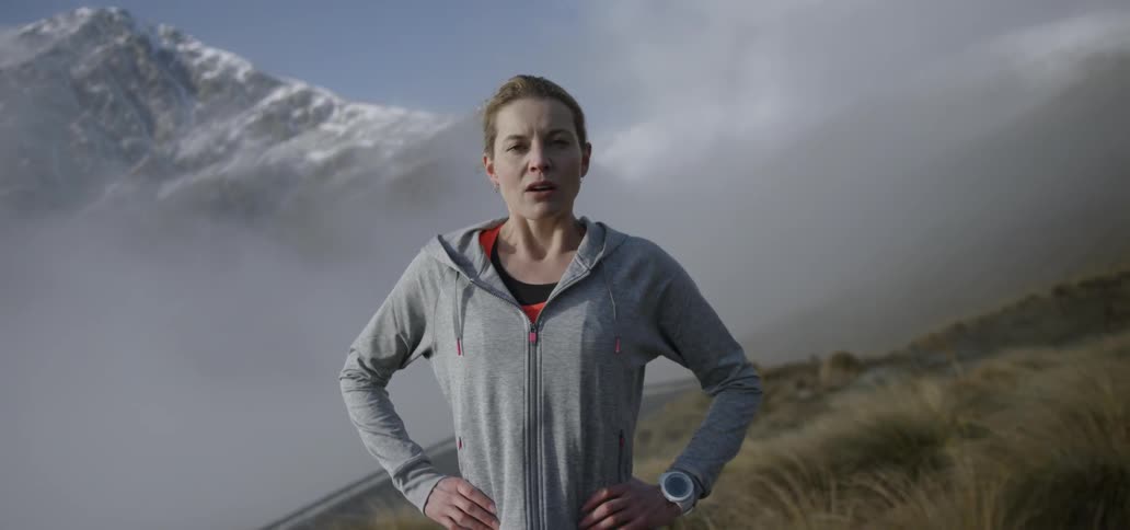 A woman is standing on a mountain breathing deep