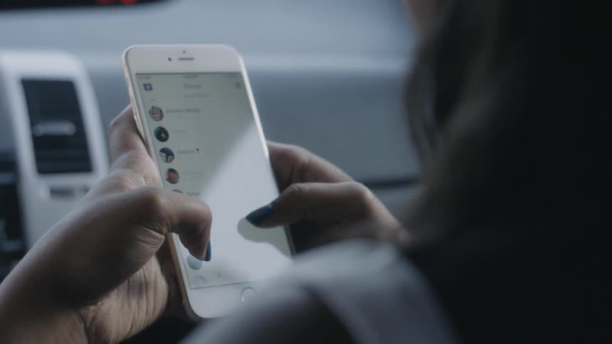 A woman is scrolling through her contacts on her cellphone