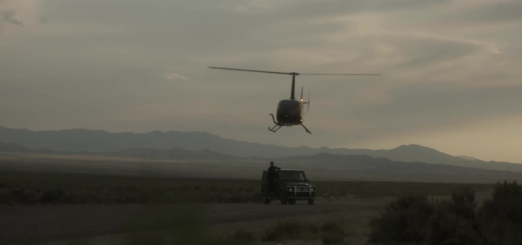 Helicopter hovers low over a jeep and person