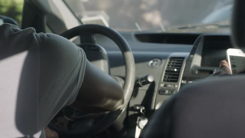 Man driving a vehicle in a city as seen from the rear seat