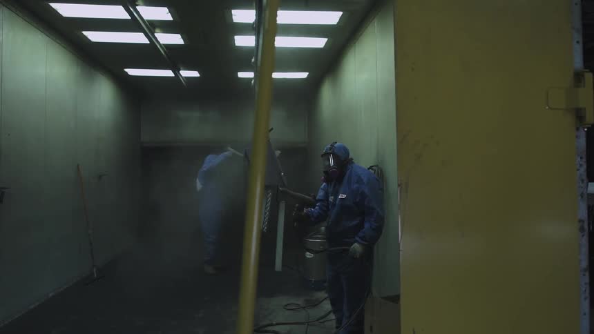 A factory worker uses a spray gun