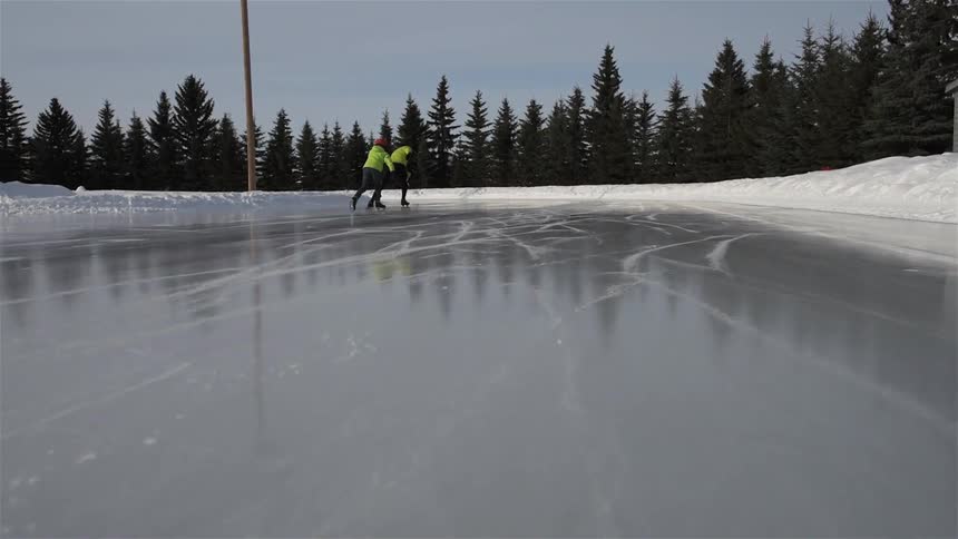 Two people are skating on an outdoor ice-skating track