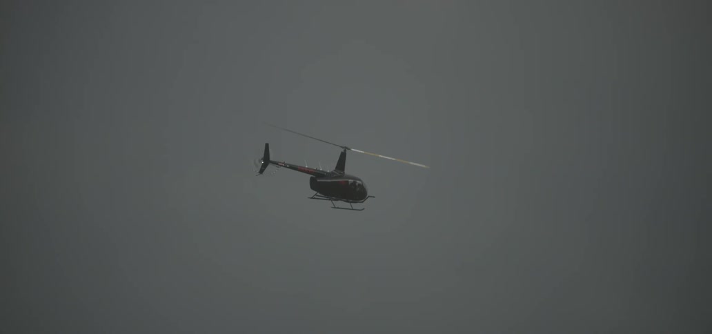 A helicopter is flying in a cloudy sky