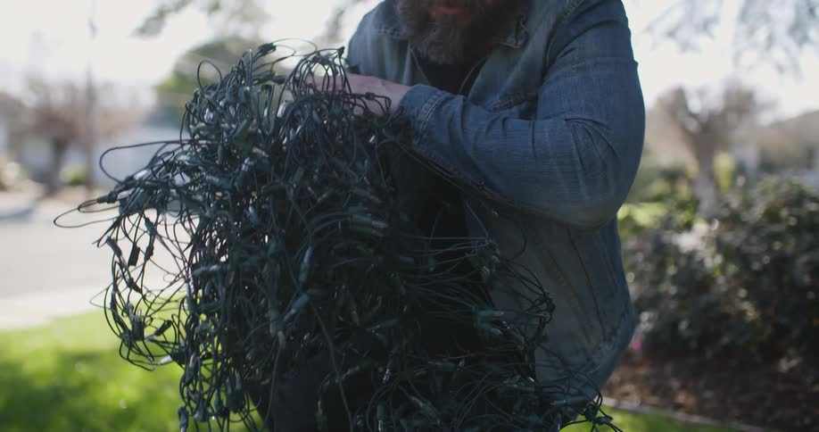 A man is pulling a tangled string of lights out of a box