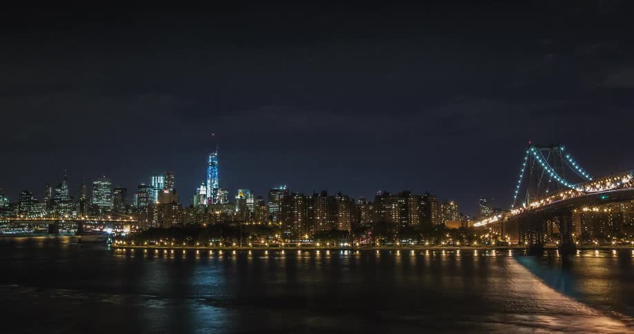 A river flows in front of a cityscape at night