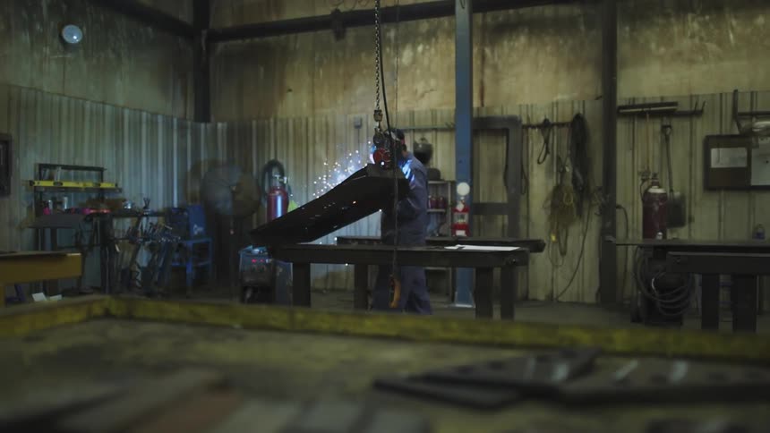 A man is welding in a shop near his bench