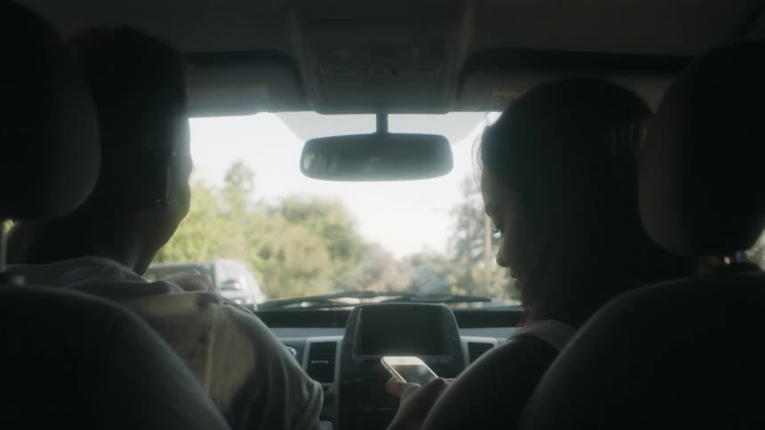 A man and woman ride in a car on a sunny day