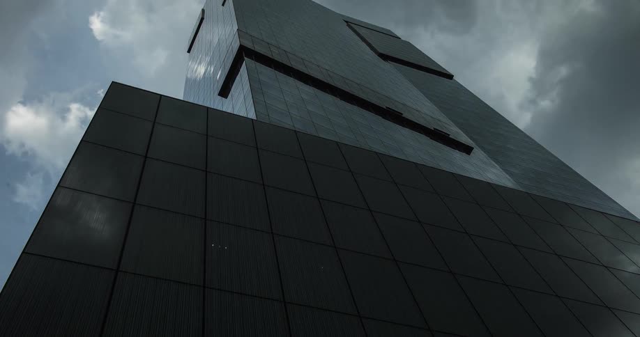 A tall office building reflects the clouds floating overhead