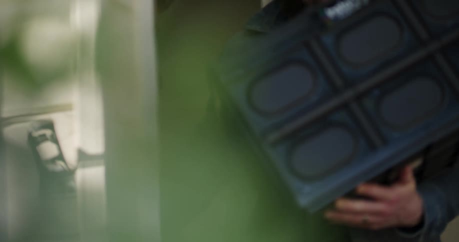 A person walks out of their house carrying a plastic box