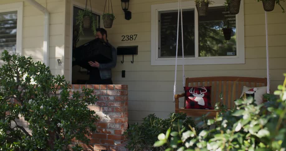 A man carrying a box walks out of his house