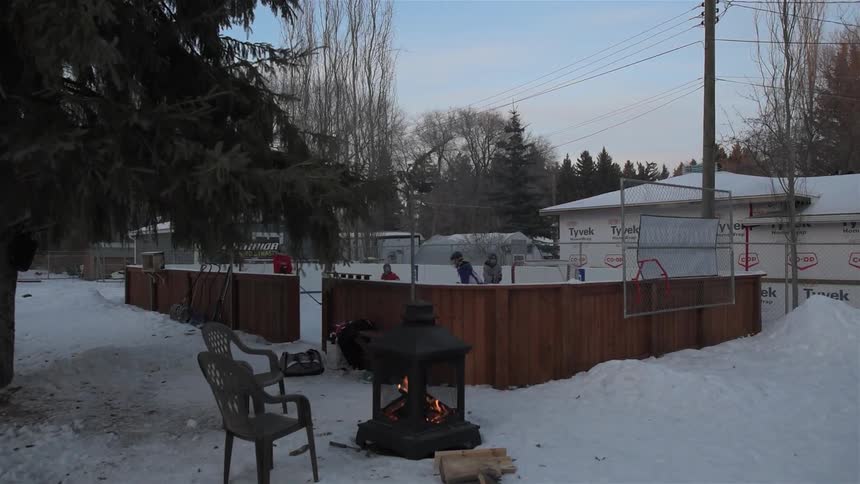 A group of kids are playing hockey in a backyard ice-rink
