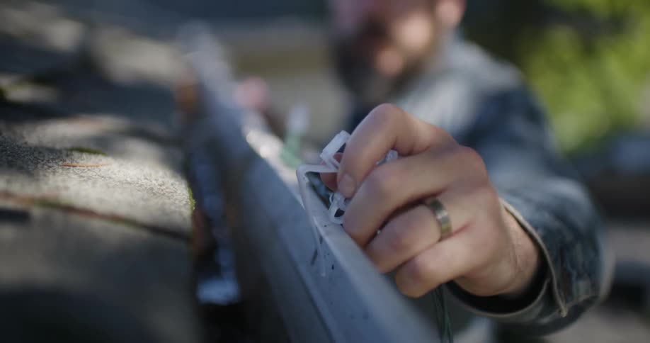 Man puts a plastic clip on a metal beam outside
