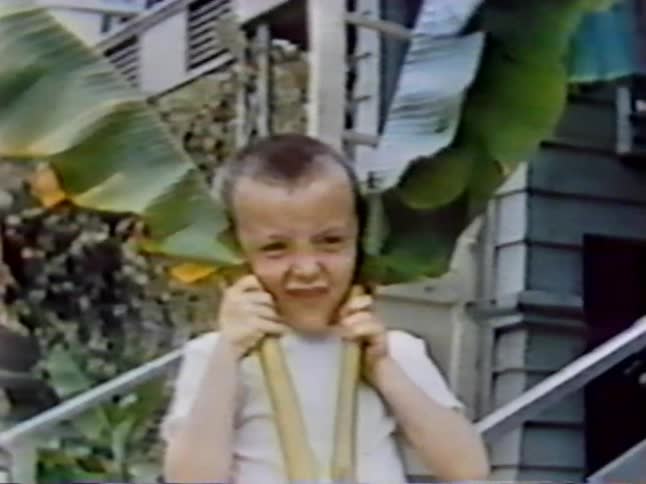 A boy raises two large branches to his ears