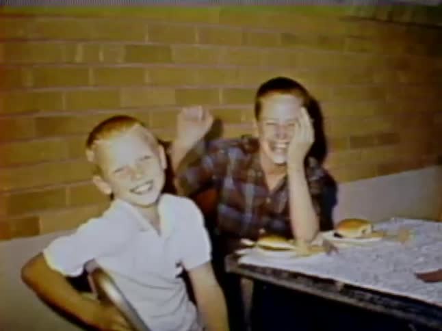 Two children are sitting down to a meal laughing