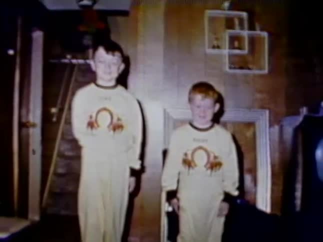 Two children stand together in a living room