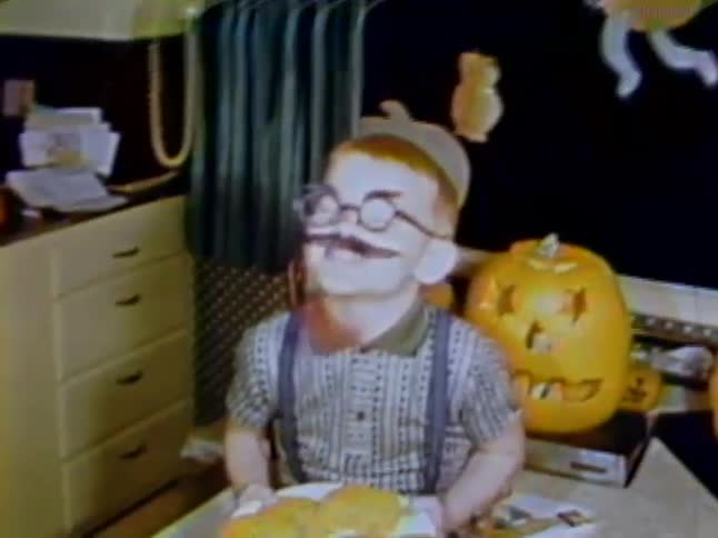 A child has fake mustache lips and glasses on