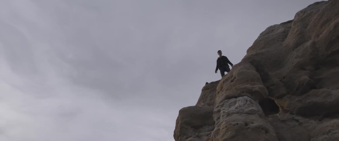 Man stands at the edge of a rocky cliff