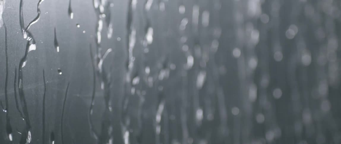 Water drizzling down a piece of glass