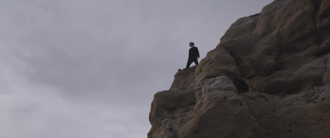 A man stands on the edge of a cliff