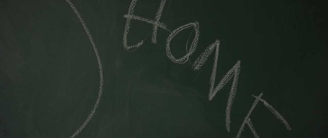 Hand scribbling on a chalkboard with chalk