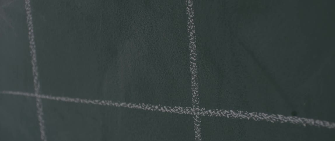 A person draws an x on the chalkboard