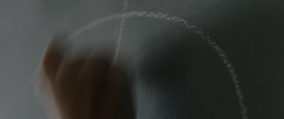 Hand scribbling on a chalkboard with chalk