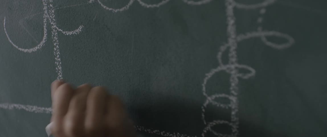 Hand scribbling on a chalkboard with chalk