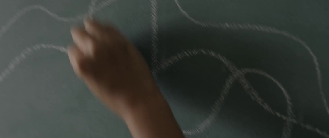 Hand scribbling on a chalkboard with chalk