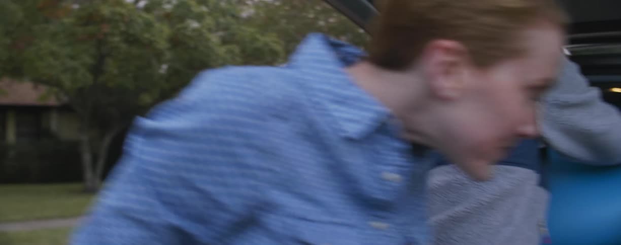 A man and woman are trying to stuff an object into the back an suv